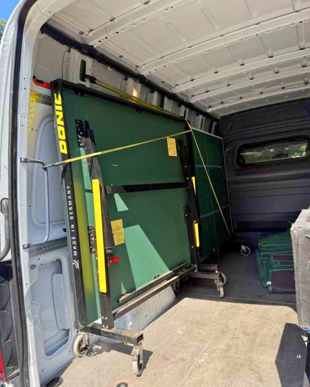 Folded green ping pong table secured inside a Lugg van, prepped for game night delivery.