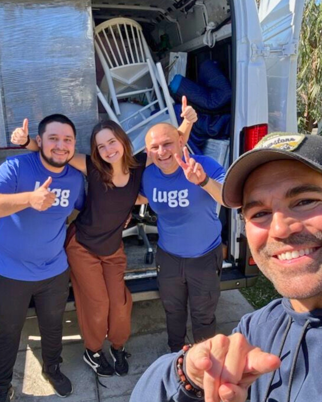 Luggers pose with a smiling customer (Bailee Madison) in front of a packed moving truck filled with chairs and wrapped furniture, celebrating a smooth Marketplace pickup and delivery.