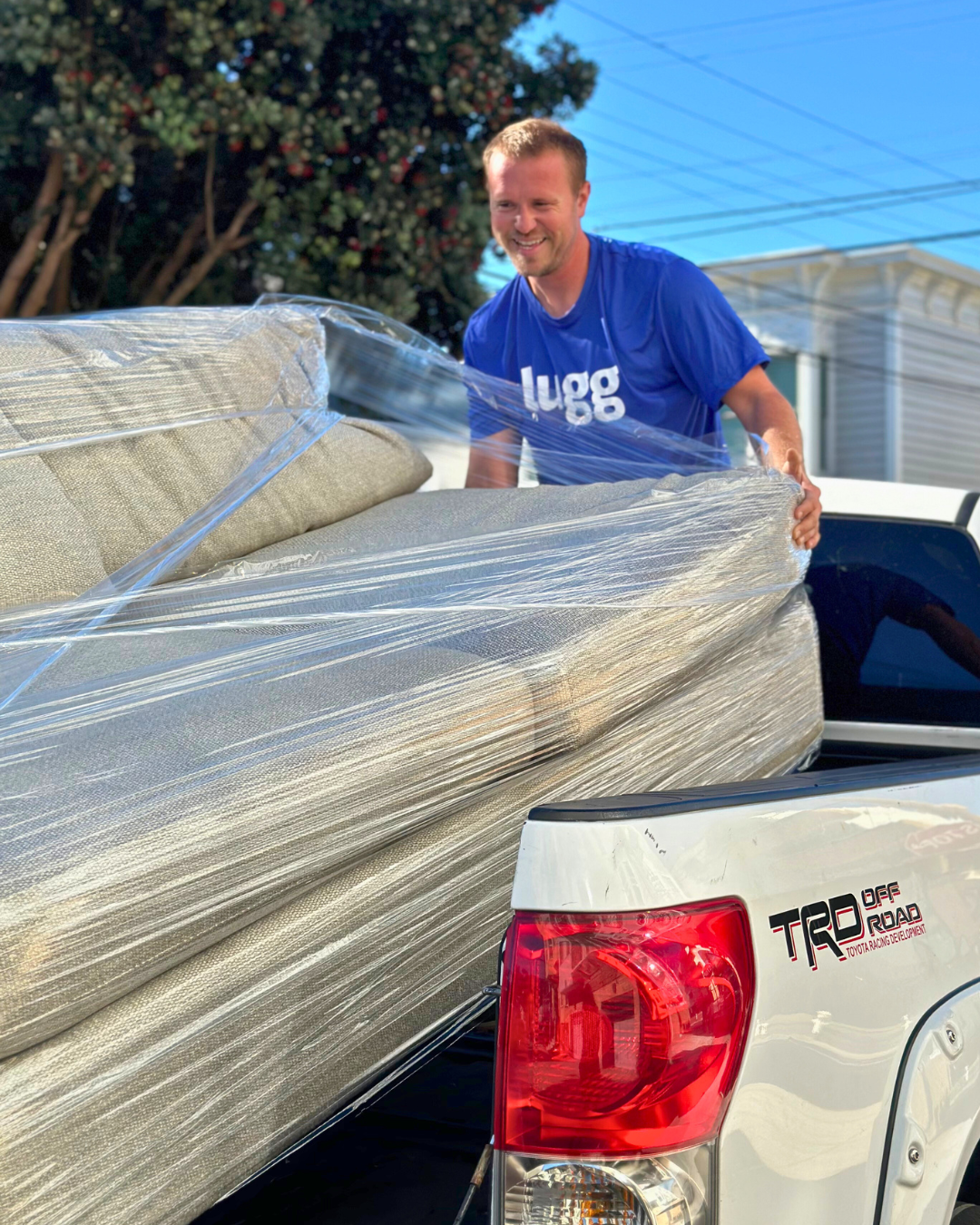 Lugg Helper wrapping and loading a couch into the back of a truck during a move.