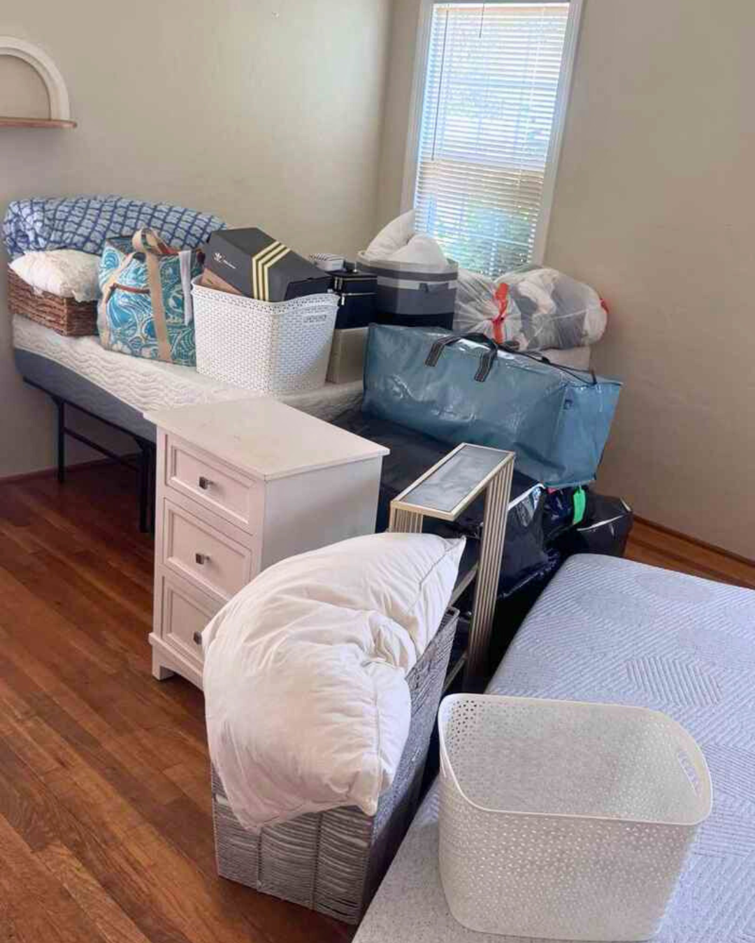 College dorm bedroom filled with packed bins, bedding, and storage ready for move-in.
