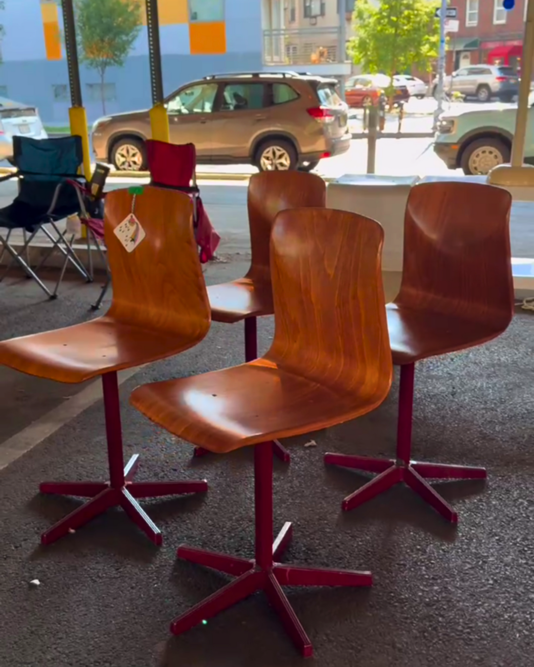 Four vintage wooden swivel chairs with red metal bases on display at BQ Flea.