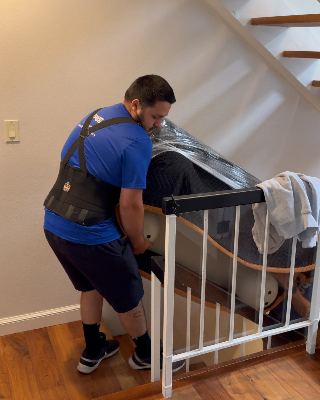 Lugg mover lifting a wrapped item up a staircase during an indoor furniture move.