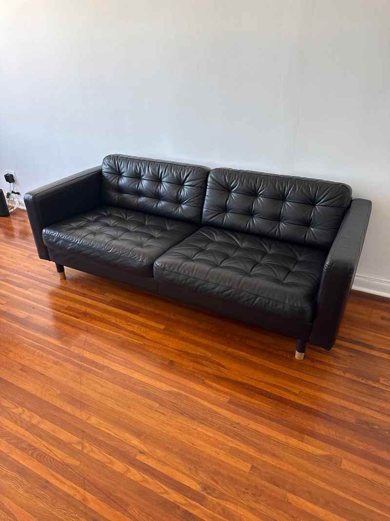 Black leather couch set up in a living room after successful local delivery from a marketplace purchase.