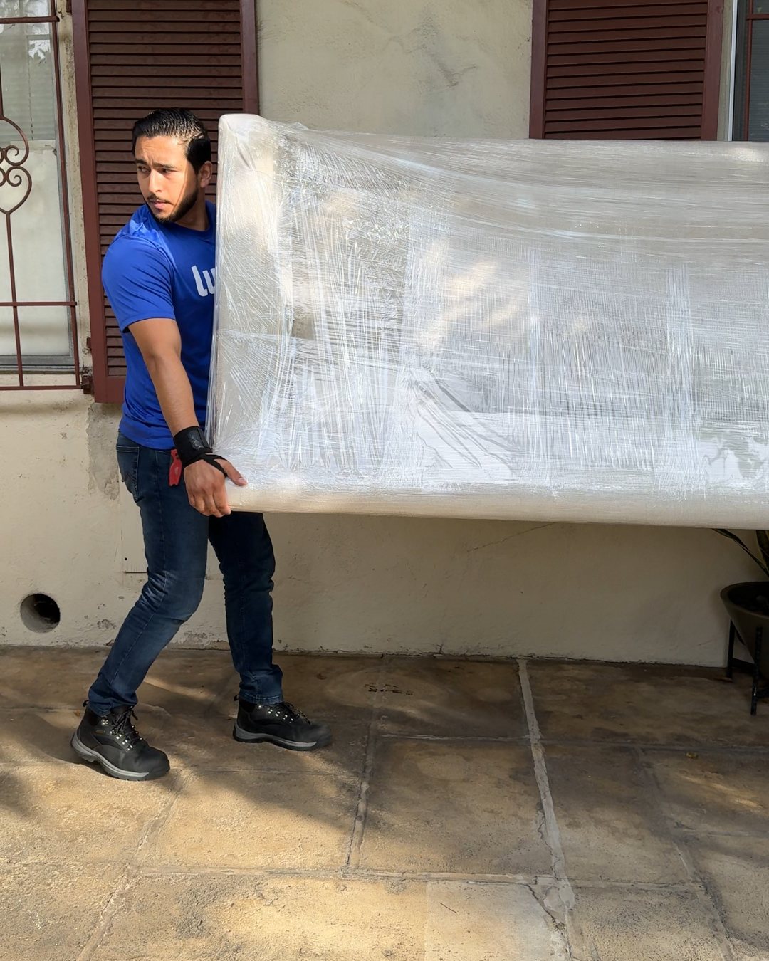 A Lugger is carrying a fully wrapped couch during a home move.