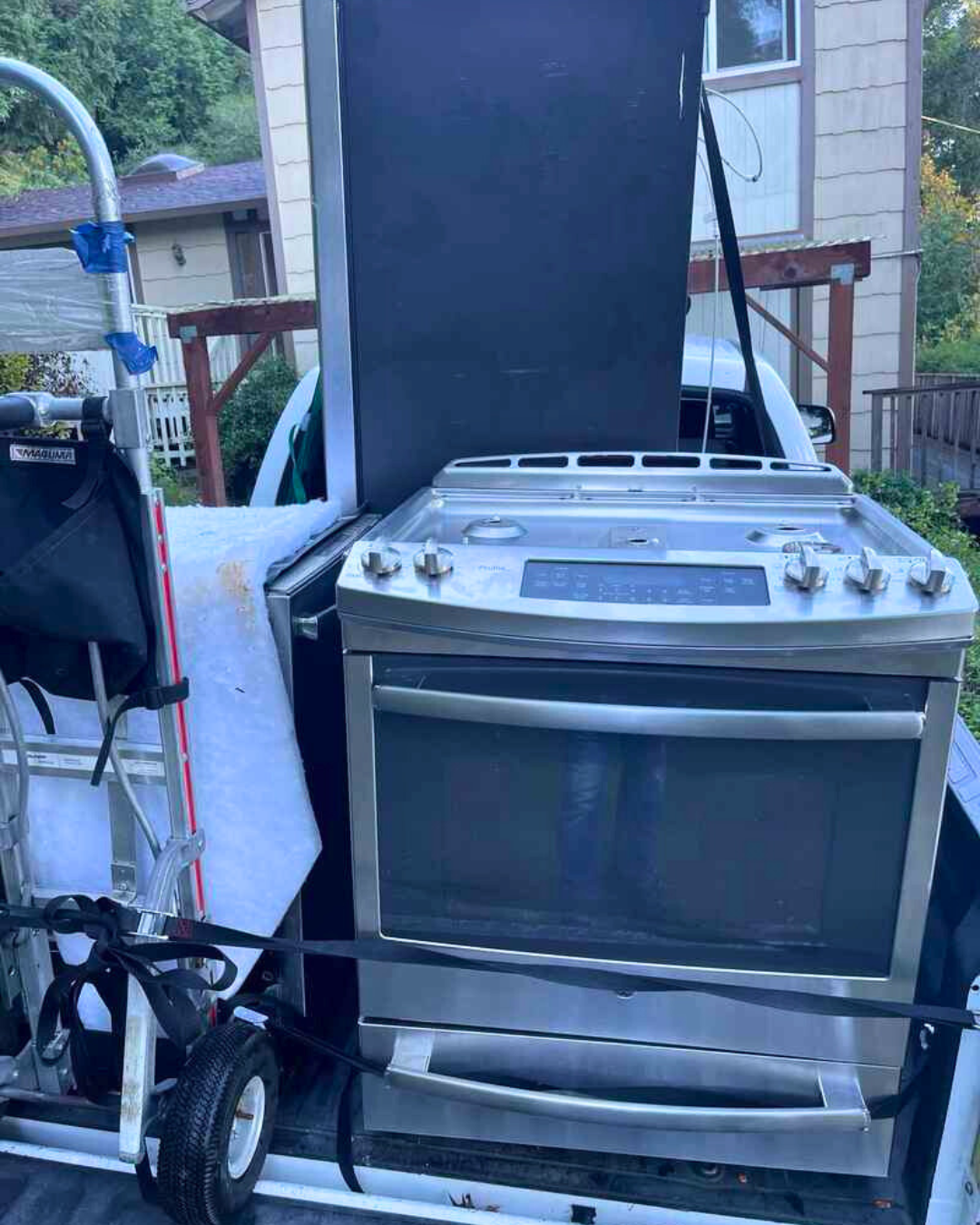 A stainless-steel oven strapped and padded inside a moving truck as Luggers prepare it for safe transport to a donation center.