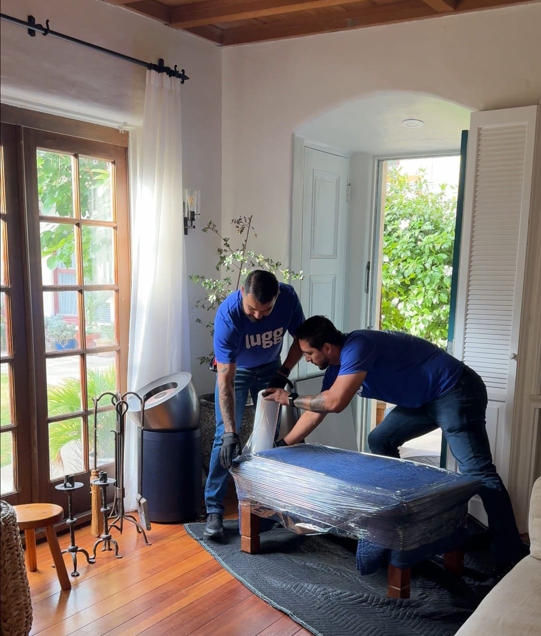 Lugg movers carefully wrapping furniture with moving blankets and other protective material inside a home