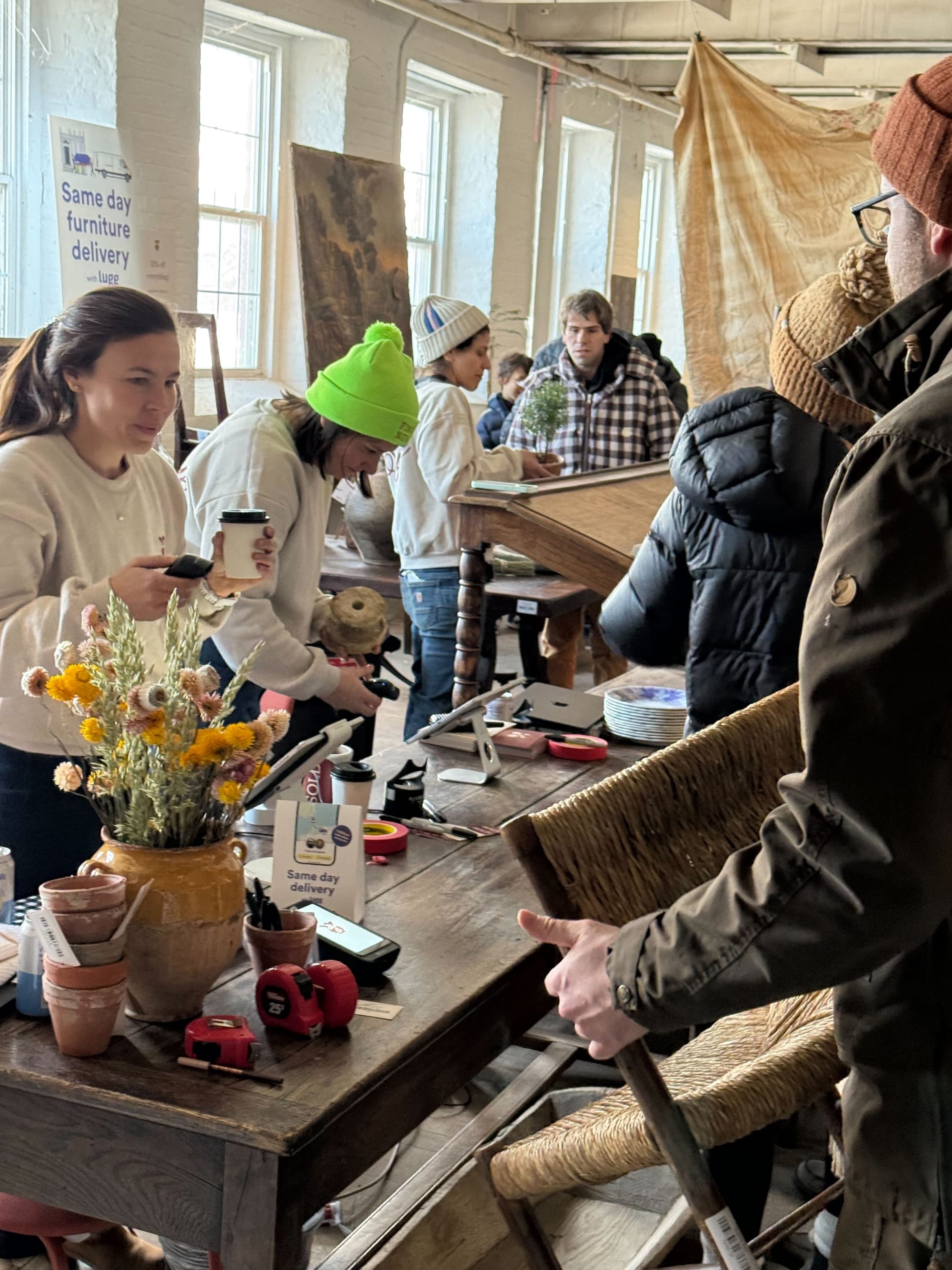 Busy checkout area at Sylvie Estate Sale with Lugg same day delivery sign visible