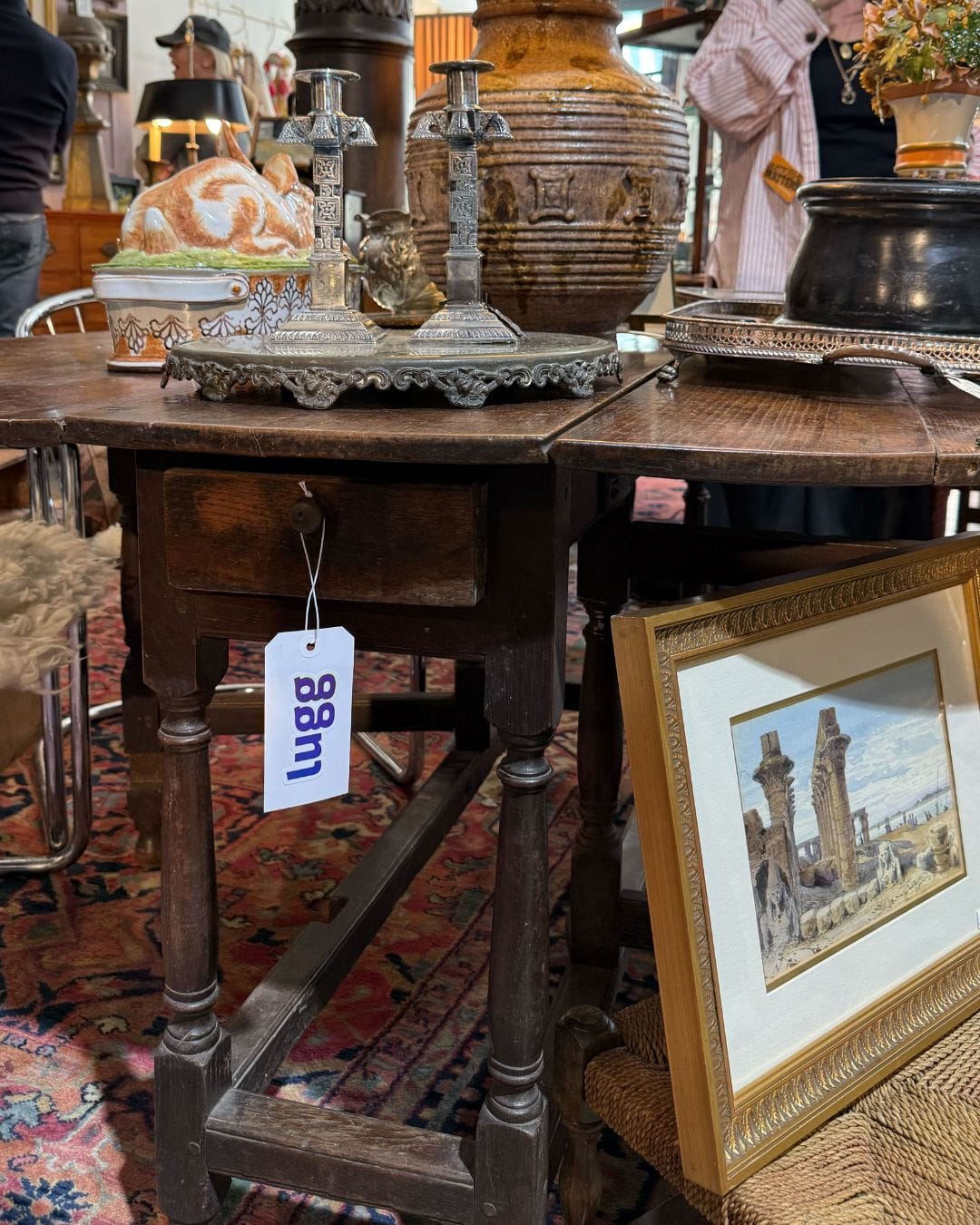 Lugg delivery tag hanging from a vintage wooden table with silver candlesticks at Material Matters NYC